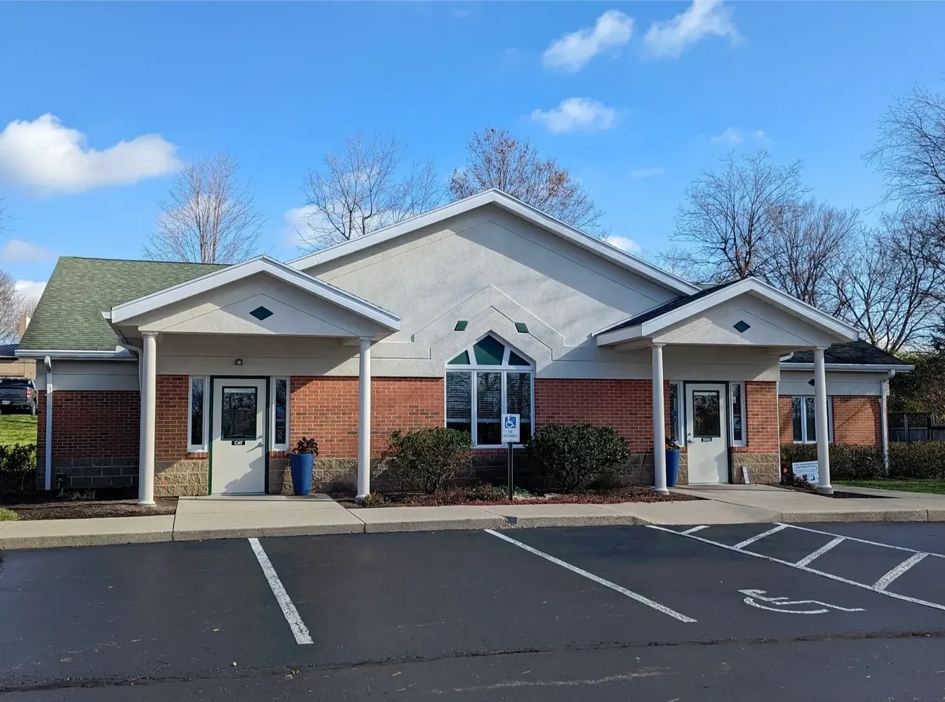 Brick and stone veterinary clinic building in Centerville Ohio with covered entrance porches, accessible parking, and bare trees in early spring